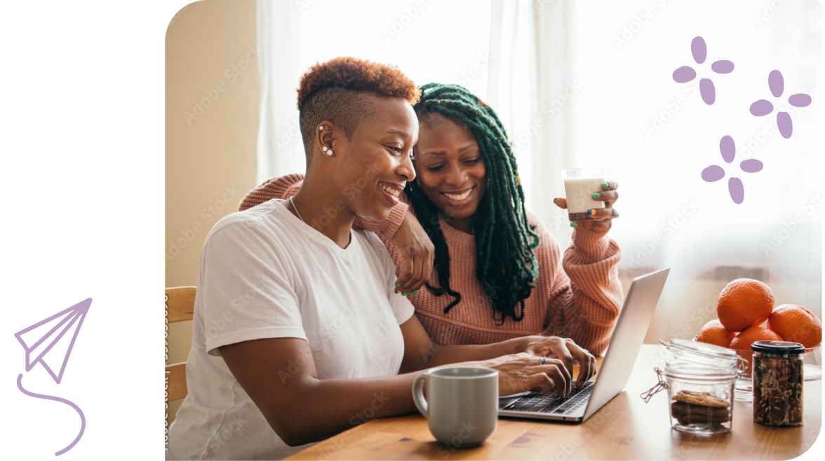Two women drinking coffee while looking at a laptop.